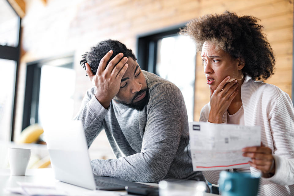 Two people looking concerned while examining a document in a home office setting