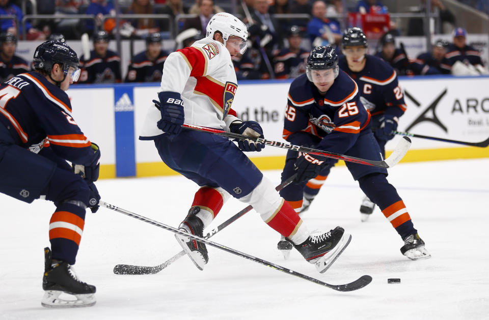 Florida Panthers center Eric Staal falls backward between New York Islanders defensemen Scott Mayfield, left, and Sebastian Aho (25) during the first period of an NHL hockey game Friday, Dec. 23, 2022, in Elmont, N.Y. (AP Photo/John Munson)
