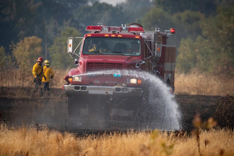 A firetruck mops up the edges of a brush fire on the east end of Alton Baker Park near the Knickerbocker Bike Bridge on Aug. 25 in Eugene.