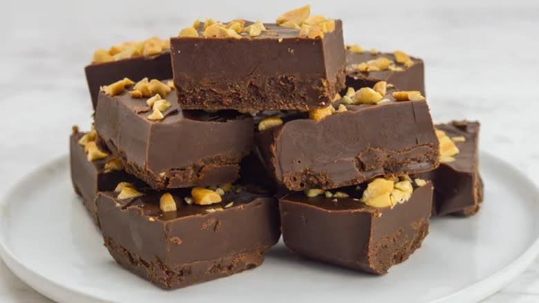 A plated stack of keto fudge pieces with peanut toppings