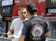 A police officer warns a maskless man in Ankara, Turkey, Thursday, June 18, 2020. Turkish authorities have made the wearing of masks mandatory in three major cities to curb the spread of COVID-19 following an uptick in confirmed cases since the reopening of many businesses.(AP Photo/Burhan Ozbilici)
