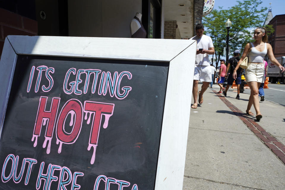 With temperatures hovering in the mid-90's, people walk near a sign down Hanover Street in the North End, during a summer heat wave, Thursday, July 21, 2022, in Boston. Dangerously high temperatures Thursday threatened much of the Northeast and Deep South as millions of Americans sought comfort from air-conditioners, fire hydrants, fountains and cooling centers. (AP Photo/Charles Krupa)