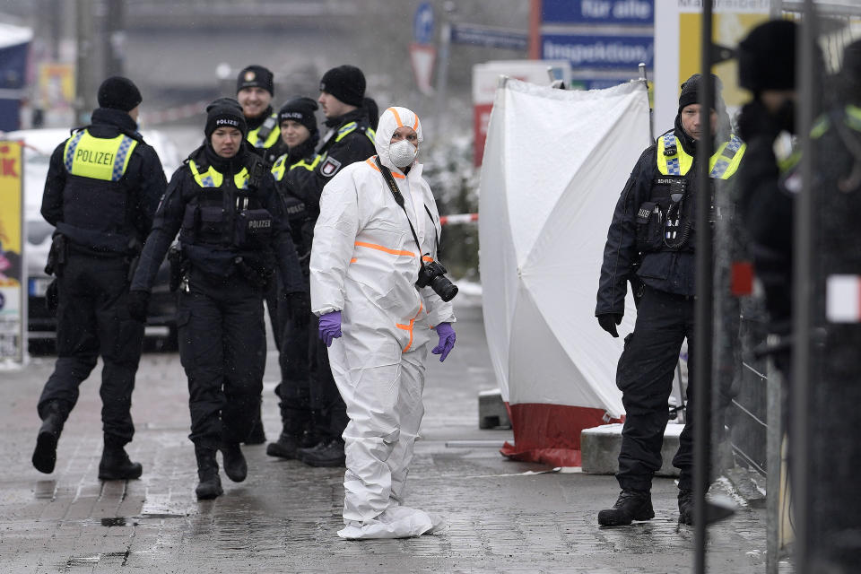 A forensic expert stands beside police outside a Jehovah's Witness building in Hamburg, Germany Friday, March 10, 2023. Shots were fired inside the building used by Jehovah's Witnesses in the northern German city of Hamburg on Thursday evening, with multiple people killed and wounded, police said. (AP Photo/Markus Schreiber)