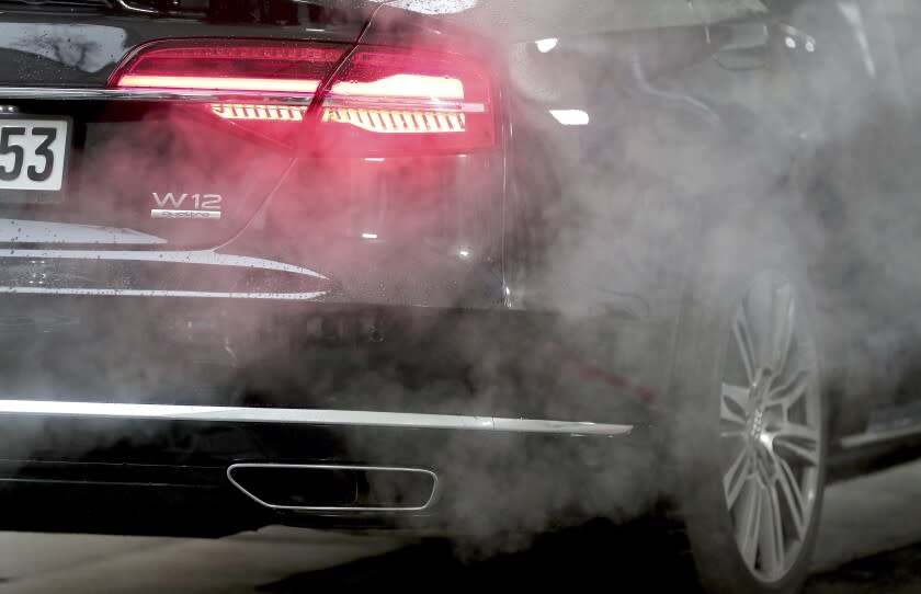 A luxury Audi car is surrounded by exhaust gases as it is parked with a running engine in front of the Chancellery in Berlin, Germany, Wednesday, Nov. 20, 2019. Germany's transport minister said Thursday that he opposes plans to ban the sale of new cars with combustion engines across the European Union in 2035, arguing this would discriminate against vehicles powered with synthetic fuels. EU lawmakers voted Wednesday to back the measure that requires automakers to cut carbon-dioxide emissions by 100% by the middle of the next decade, effectively prohibiting the sale in the 27-nation bloc of new cars powered by gasoline or diesel. (AP Photo/Michael Sohn, File)