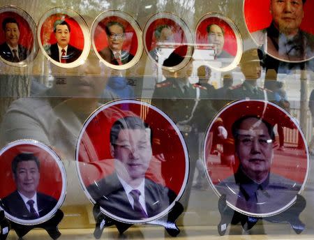 Paramilitary policemen and pedestrians are reflected in a window of a shop selling souvenirs bearing the pictures of China's President Xi Jinping and former leaders near the Great Hall of the People in Beijing in this October 23, 2014 file photo. REUTERS/Kim Kyung-Hoon/Files