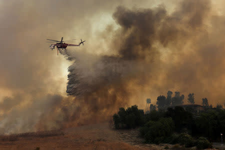 A firefighting helicopter drops water to help save a home during a wind driven wildfire in Orange, California, U.S., October 9, 2017. REUTERS/Mike Blake