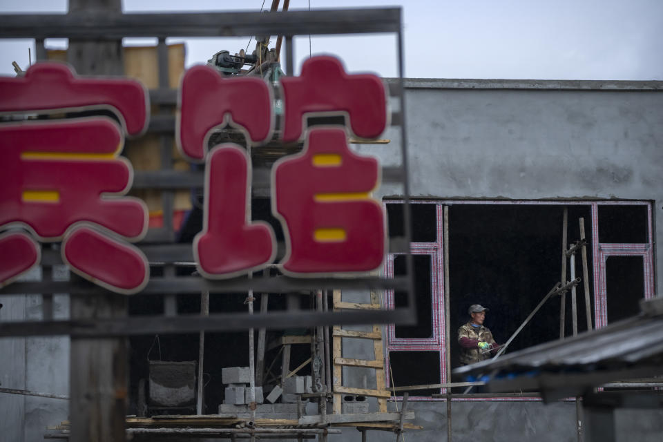 A construction worker labors at a hotel being built in a neighborhood of tourist homestays in Zhaxigang village near Nyingchi in western China's Tibet Autonomous Region, Friday, June 4, 2021. Tourism is booming in Tibet as more Chinese travel in-country because of the coronavirus pandemic, posing risks to the region's fragile environment and historic sites. (AP Photo/Mark Schiefelbein)