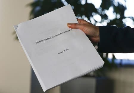 A journalist shows off the independent commission report ahead of a news conference by the World Anti-Doping Agency's (WADA) former president, Dick Pound, who heads the commission into corruption and doping in athletics, in Unterschleissheim near Munich, Germany, January 14, 2016. REUTERS/Michael Dalder