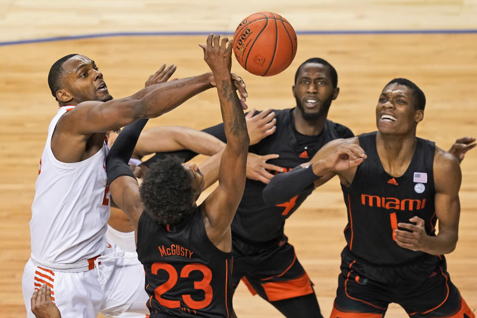 Clemson forward Aamir Simms, left, battles for a rebound with Miami guard Kameron McGusty (23) and teammates Anthony Walker, right, and Elijah Olaniyi, second from right, during the second half of an NCAA college basketball game in the second round of the Atlantic Coast Conference tournament in Greensboro, N.C., Wednesday, March 10, 2021. (AP Photo/Gerry Broome)
