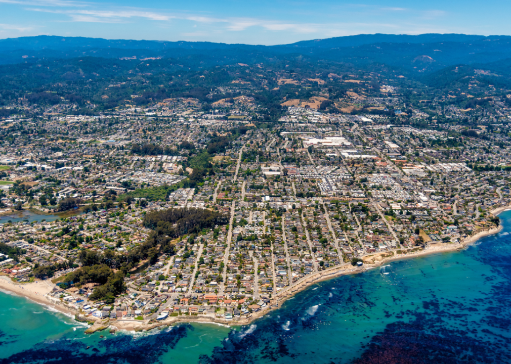 Aerial view of a city surrounded by mountains and body of water.