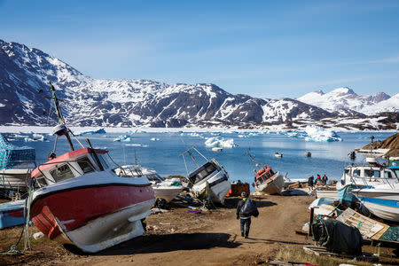 FILE PHOTO: A man walks to his boat past a number of abandoned and dry-docked boats in the town of Tasiilaq, Greenland, June 15, 2018. REUTERS/Lucas Jackson/File Photo