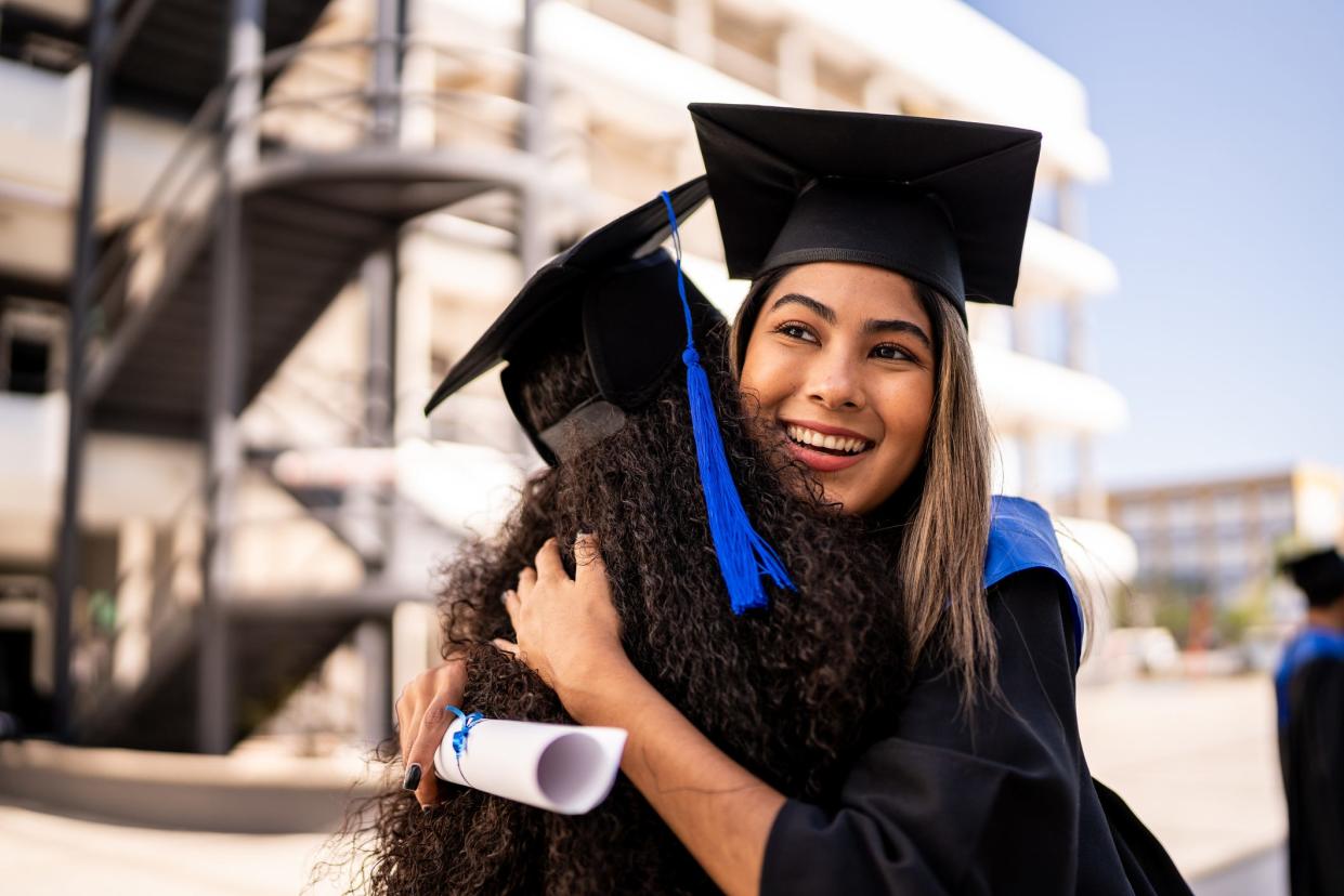 Graduating student looking into the distance while hugging another classmate