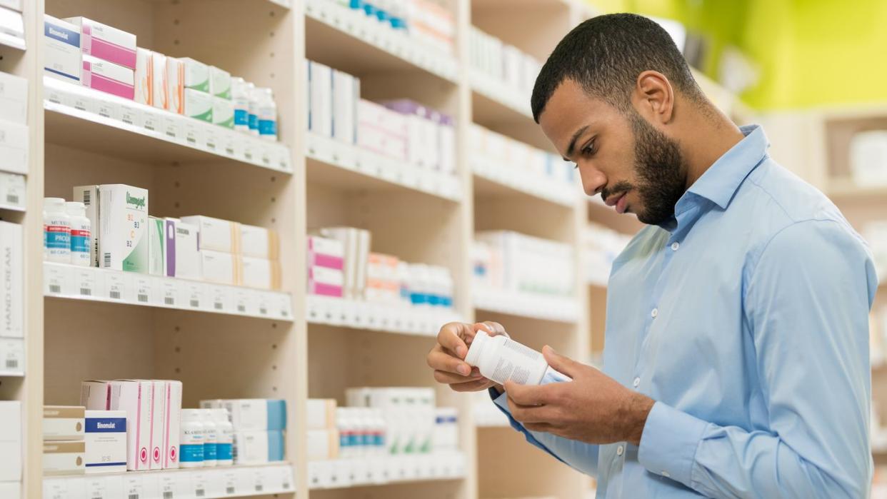 beard man choosing supplement in drugstore