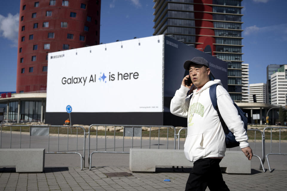 A man uses a mobile phone as he walks past outside Fira Barcelona, venue of the Mobile World Congress (MWC), in Barcelona on February 23, 2024. The world's biggest mobile phone fair throws open its doors in Barcelona on February 26 with the sector looking to artificial intelligence to try and reverse declining sales. Phone makers are expected to focus on the unique AI-powered tools of their latest handsets at the four-day Mobile World Congress in Barcelona where 95,000 attendees and 2,400 exhibitors from around the world are awaited for this event. (Photo by Josep LAGO / AFP) (Photo by JOSEP LAGO/AFP via Getty Images)