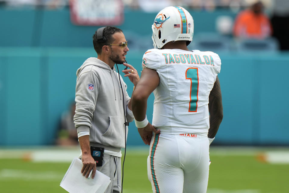 Miami Dolphins head coach Mike McDaniel talks to quarterback Tua Tagovailoa (1) during the second half of an NFL football game against the Carolina Panthers, Sunday, Oct. 15, 2023, in Miami Gardens, Fla. (AP Photo/Wilfredo Lee)