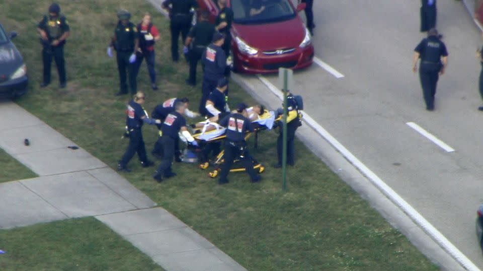 Paramedics rush an injured person from the high school. Source: AAP