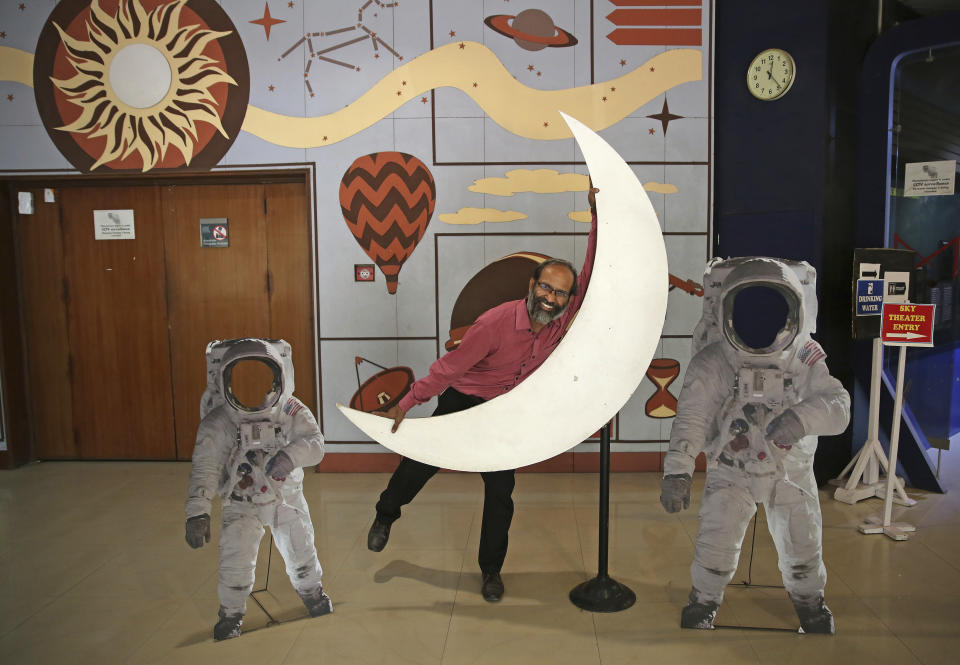 An employee playfully hugs a cut-out of a crescent moon at the Nehru Planetarium in New Delhi, India, Thursday, July 11, 2019. India is looking to take a giant leap in its space program and solidify its place among the world’s spacefaring nations with its second unmanned mission to the moon, this one aimed at landing a rover near the unexplored south pole. (AP Photo/Altaf Qadri)