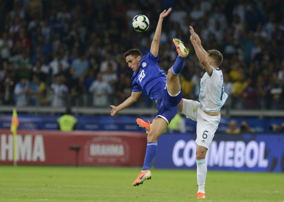 Paraguay's Matias Rojas, left, and Argentina's German Pezzella jump for the ball during a Copa America Group B soccer match at the Mineirao stadium in Belo Horizonte, Brazil, Wednesday, June 19, 2019. (AP Photo/Eugenio Savio)