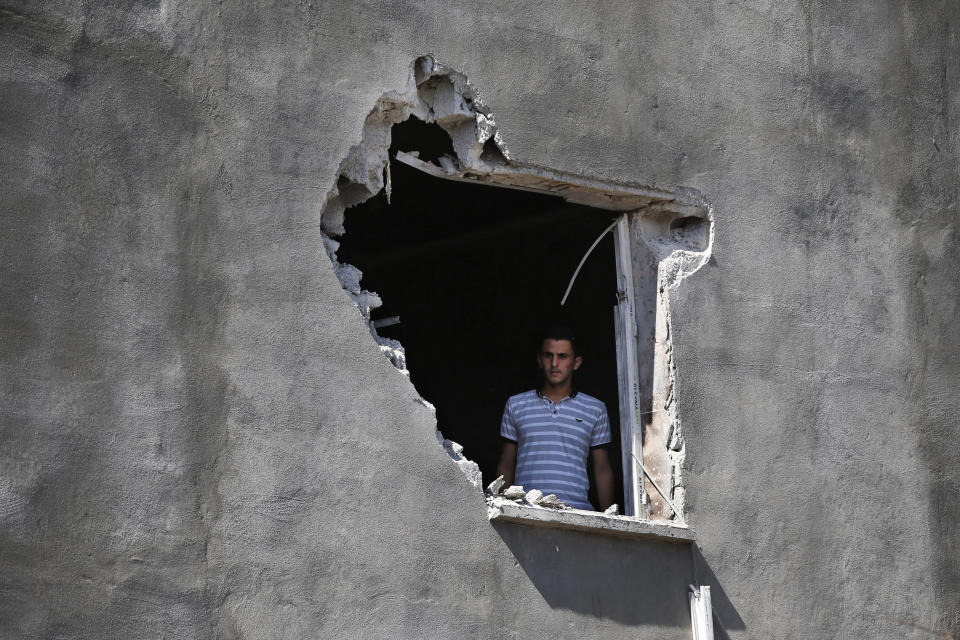 FILE-In this Saturday, Oct. 12, 2019 file photo, a local resident looks out from a hole on a house that was damaged by a mortar fired from inside Syria, on the Turkish town of Akcakale, southeastern Turkey. Since Turkey announced its incursion into neighbouring Syria to clear out Kurdish fighters last week, patriotic sentiment has run high. (AP Photo/Lefteris Pitarakis, File)