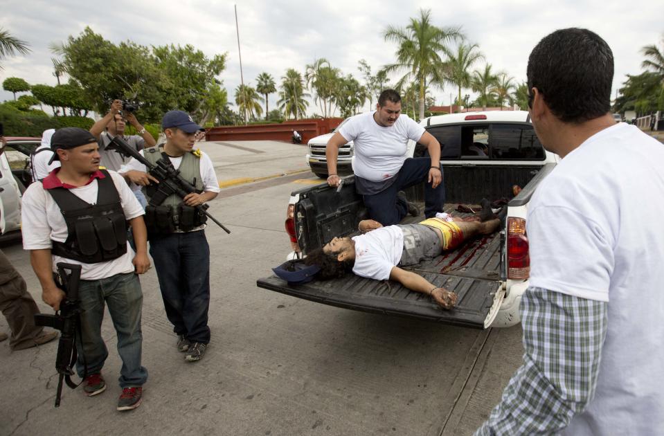 A wounded man belonging to the Self-Defense Council of Michacan, (CAM), is taken away during a firefight while trying to flush out alleged members of the Knights Templar drug cartel from the town of Nueva Italia, Mexico, Sunday Jan. 12, 2014. The vigilantes say they are liberating territory in the so-called Tierra Caliente and are aiming for the farming hub of Apatzingan, said to be the cartel's central command. Mexican military troops are staying outside the town and there are no federal police in sight. (AP Photo/Eduardo Verdugo)