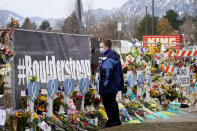 Amber Van Brocklin looks at the crosses displayed along a temporary fence set up around the parking lot of a King Soopers grocery store where a mass shooting took place earlier in the week, Thursday, March 25, 2021, in Boulder, Colo. (AP Photo/David Zalubowski)