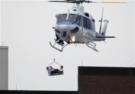 A helicopter pulls what appears to be a shooting victim up as it hovers over a rooftop on the Washington Navy Yard campus in Washington, September 16, 2013. REUTERS/Jason Reed