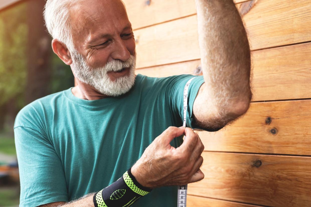 Conscious sportsman measuring his biceps size