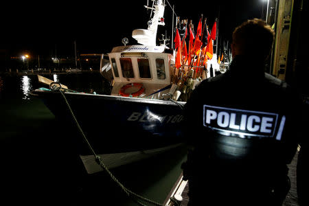 A French policeman walks past trawlers, during a patrol of the harbour in Boulogne-sur-Mer, France, January 11, 2019. Picture taken January 11, 2019. REUTERS/Pascal Rossignol