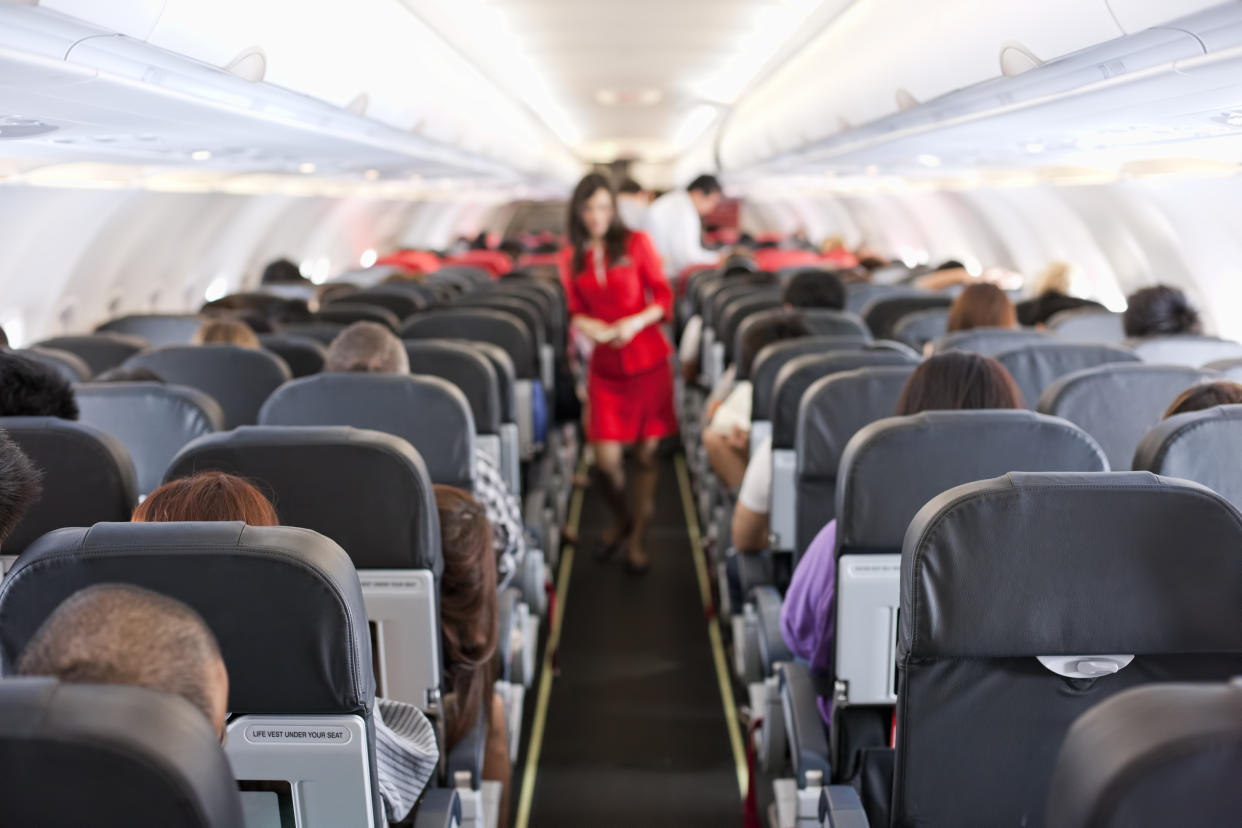 Passengers inside the cabin of a commercial airliner during flight. Shallow depth of field with focus on the seats in the foreground.