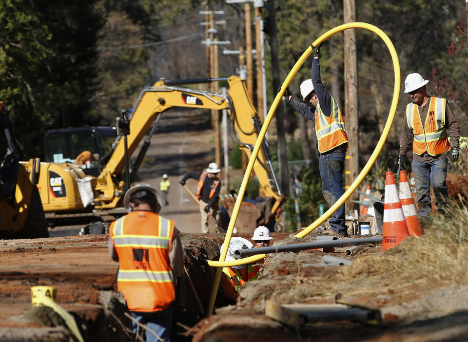 FILE - In this Oct. 18, 2019, file photo, Pacific Gas and Electric Company workers bury utility lines in Paradise, Calif. Pacific Gas and Electric said Tuesday, Feb. 18, 2020, that it expects to become more profitable than ever after it emerges from bankruptcy and pays off more than $25 billion in losses sustained in catastrophic wildfires ignited by its outdated equipment. (AP Photo/Rich Pedroncelli, File)