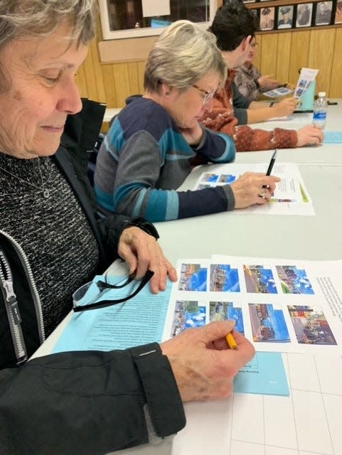 Kathy Earl and Nancy Halverson look over photos featuring suggested improvements for downtown Colon during a program Tuesday, Nov. 29, 2022, at the American Legion.