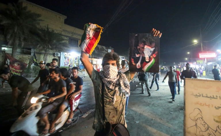 An Iraqi protester holds up a portrait of Iran's former and current supreme leaders along with an Iranian flag in Basra on September 7, 2018