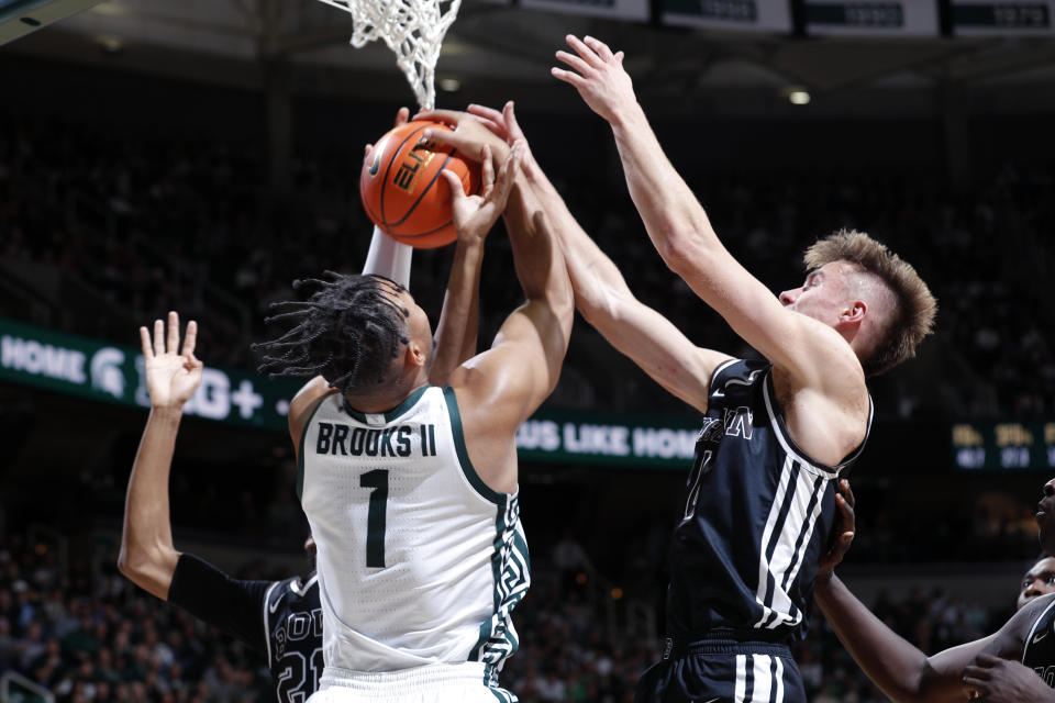 Michigan State's Pierre Brooks, center, and Brown's Paxson Wojcik, right, and Aaron Cooley vie for a rebound during the first half of an NCAA college basketball game, Saturday, Dec. 10, 2022, in East Lansing, Mich. (AP Photo/Al Goldis)