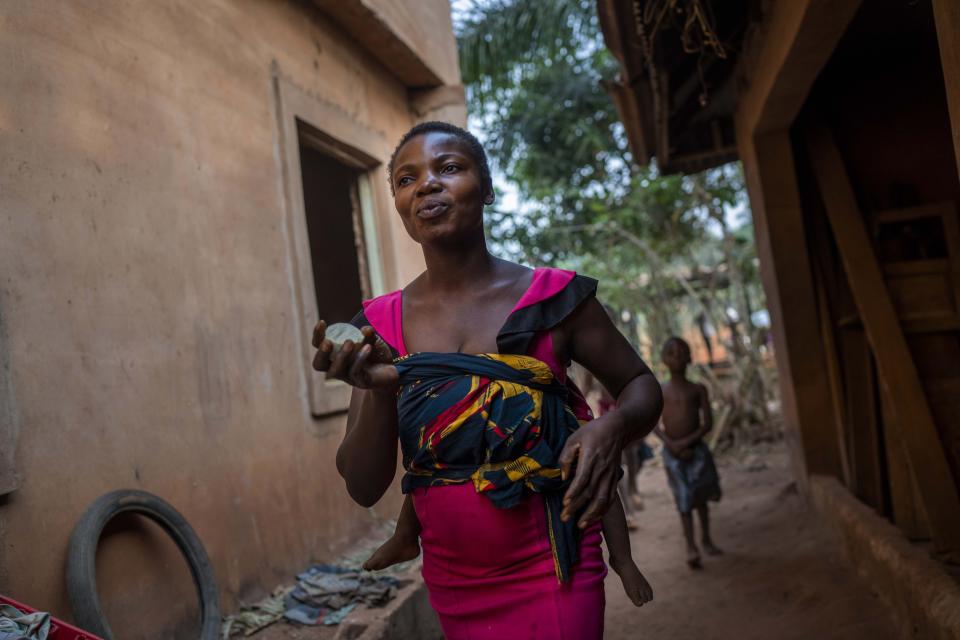 Anayo Mbah, 29, gets ready to bathe her children in her home in Umuida, Nigeria, Saturday, Feb. 12, 2022. Mbah was in the final days of her sixth pregnancy when her husband, Jonas, fell ill with fever. By the time he was taken to a clinic, the motorcycle taxi driver was coughing up blood. He tested positive for COVID-19 and was still in the hospital when she gave birth days later. The baby would never meet her father. (AP Photo/Jerome Delay)