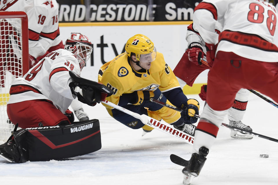 Nashville Predators left wing Tanner Jeannot (84) reaches for the puck in front of Carolina Hurricanes goaltender Alex Nedeljkovic (39) during the second period of an NHL hockey game Saturday, May 8, 2021, in Nashville, Tenn. (AP Photo/Mark Zaleski)