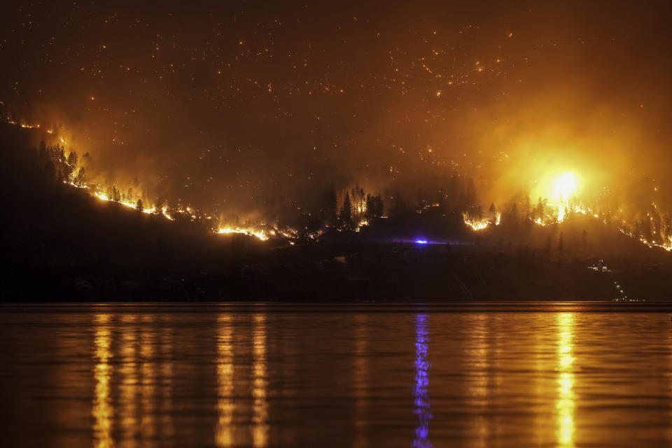 The McDougall Creek wildfire burns on the mountainside above a lakefront home in West Kelowna, Canada on Friday, Aug. 18, 2023. (Darryl Dyck/The Canadian Press via AP)