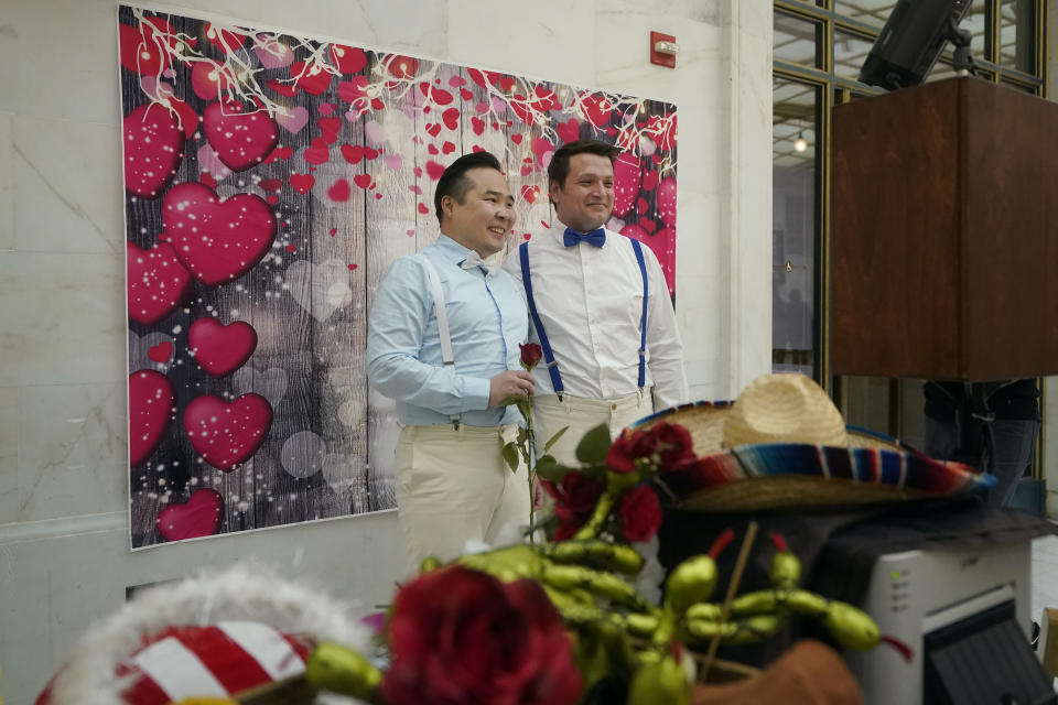 Al-Farabi Syrlybaev, left, from Moscow, smiles while posing at a photo booth after getting married to Maksim Maslovskii, from St. Petersburg, at City Hall in San Francisco, Tuesday, Feb. 14, 2023. In a state known to set the pace for the rest of the country on progressive policies, and one where its governor made news by issuing marriage licenses to same-sex couples while serving as the mayor of San Francisco, California lawmakers will attempt to enshrine marriage equality into the state's constitution. The effort comes 15 years after a voter-approved initiative, called Proposition 8, temporarily banned the state from recognizing same-sex marriages. (AP Photo/Jeff Chiu)