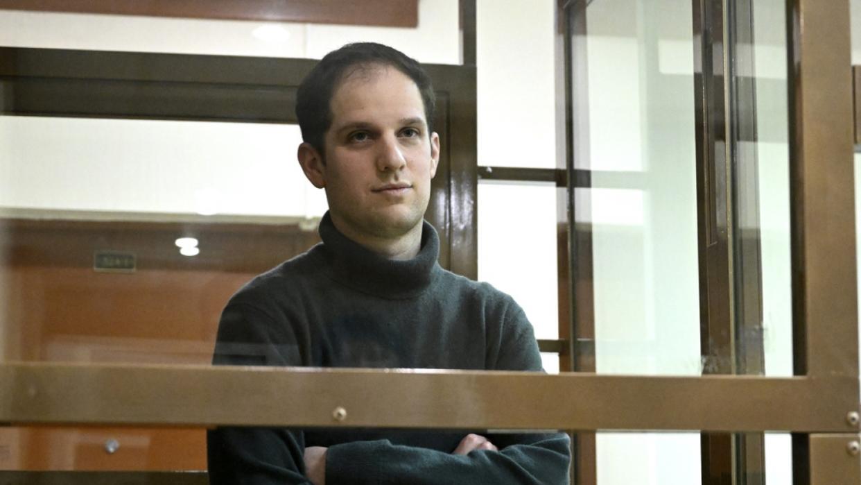 Wall Street Journal reporter Evan Gershkovich stands in a glass cage in a courtroom