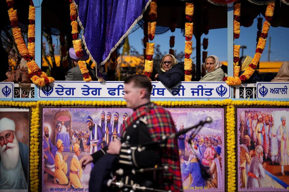 Women sit on a float carrying seniors as a bagpiper walks past them before the Vaisakhi parade in Vancouver, on Saturday, April 13, 2024. Vaisakhi is a significant holiday on the Sikh calendar, commemorating the establishment of the Khalsa in 1699 and marking the beginning of the Punjabi harvest year.