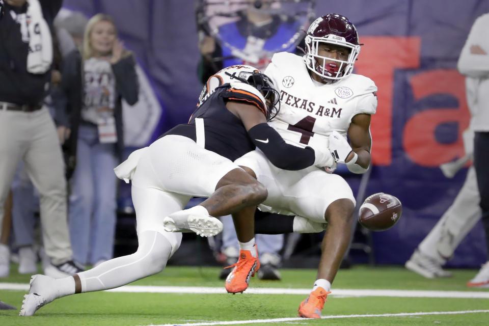 Texas A&M running back Amari Daniels (4) fumbles the ball on the tackle by Oklahoma State linebacker Xavier Benson, right, during the second half of the Texas Bowl NCAA college football game Wednesday, Dec. 27, 2023, in Houston. Oklahoma State recovered the ball. (AP Photo/Michael Wyke)