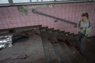 A woman walks next to the body of a man killed during shelling in Kharkiv, eastern Ukraine, Thursday, May 26, 2022. (AP Photo/Bernat Armangue)