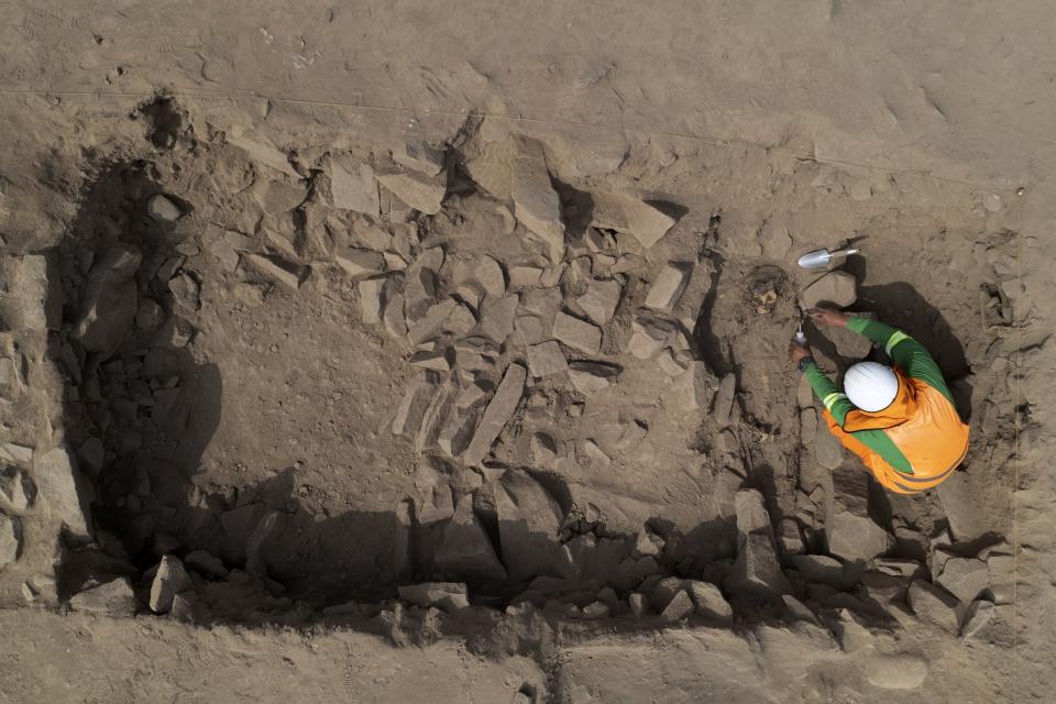 Un arqueólogo excava en la tumba de una momia prehispánica descubierta en una cima cercana a un campo de fútbol de un popular club peruano en el municipio de El Rimac de Lima, Perú, el jueves 15 de junio de 2023. (AP Foto/Martín Mejía)