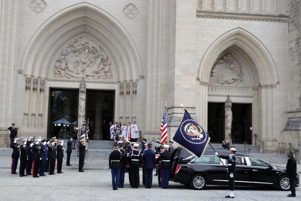 25) A joint service guard begins to carry the casket into the cathedral.