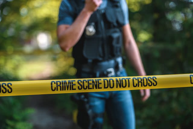 <p>Getty</p> Stock image of a police officer and crime scene tape