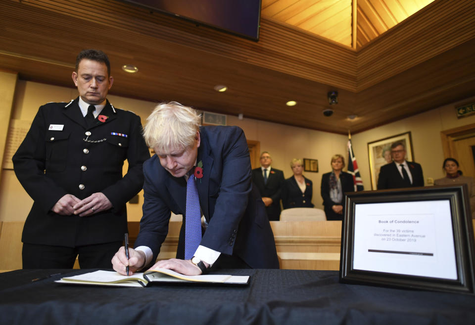 Britain's Prime Minister Boris Johnson signs a book of condolence during a visit to Thurrock Council Offices, England, Monday Oct. 28, 2019. British police say they have arrested a fourth person in connection with the deaths of 39 people found in a truck in southeast England in one of Britain's worst human-smuggling tragedies. (Stefan Rousseau/Pool via AP)