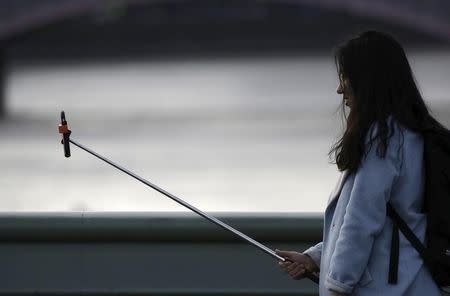 A woman takes a photo using a "selfie" stick whilst standing on Westminster Bridge in London January 10, 2015. REUTERS/Kevin Coombs