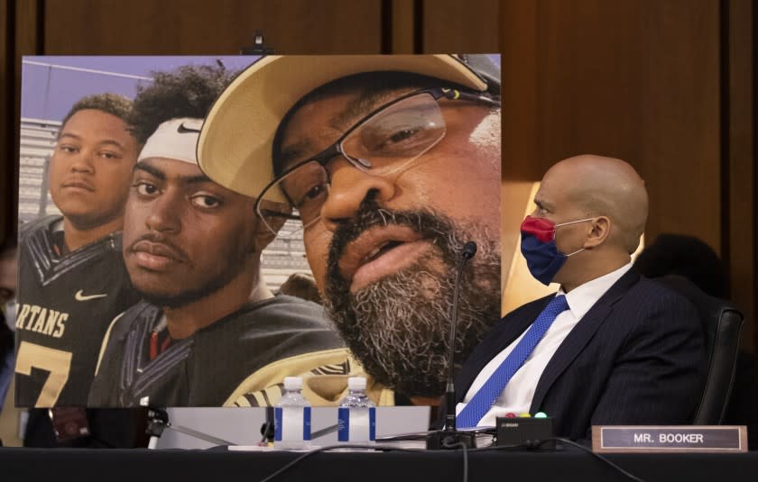 Sen. Cory Booker (D-N.J., looks on near a poster with people that benefited from the Affordable Care Act as opening statements are made for the confirmation hearing of Amy Coney Barrett before the Senate Judiciary Committee, on Capitol Hill in Washington, Monday, October 12, 2020. (Alex Edelman/Pool via AP)