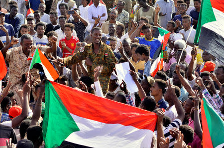 Sudanese military officer joins demonstrators as they celebrate after the Defence Minister Awad Ibn Auf stepped down as head of the country's transitional ruling military council, as protesters demanded quicker political change, near the Defence Ministry in Khartoum, Sudan April 13, 2019. REUTERS/Stringer