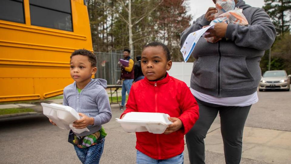 Nazir Williams, 3, left, and J-Sheer Williams, 3, walk home in March 2020 with their mother Saleemah Williams. Their lunch was provided at a Durham meal distribution site as all North Carolina public schools close in an effort to slow the spread of the coronavirus.