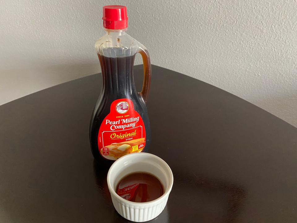 bottle of pearl milling company syrup next to a white ramekin filled with the syrup